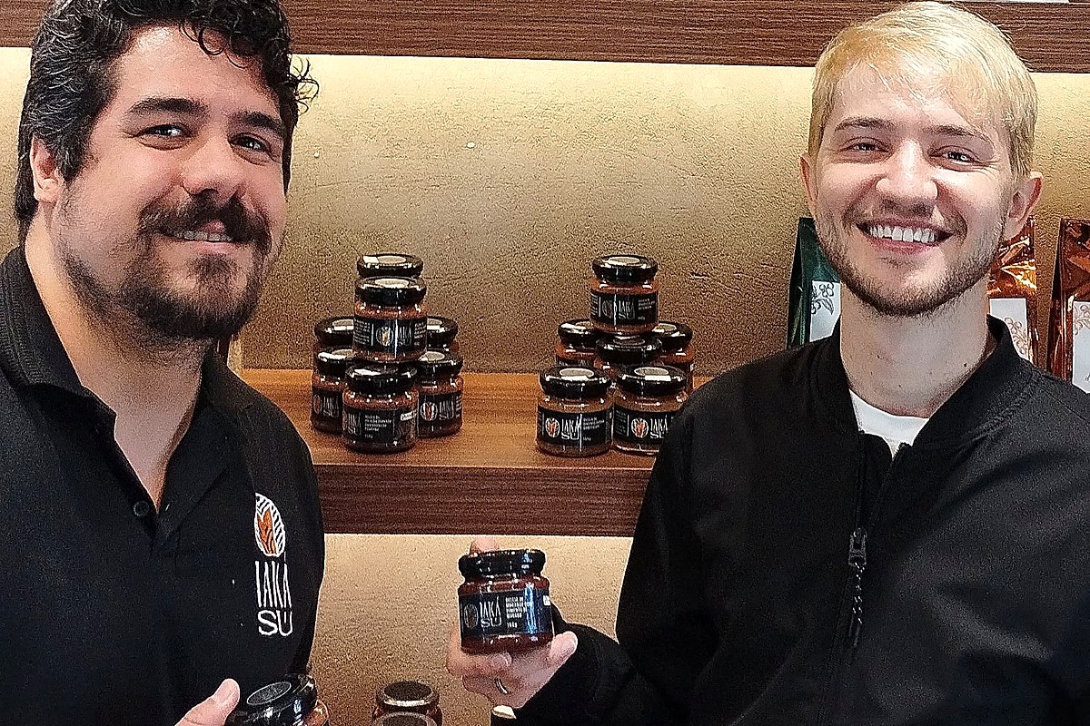 Dupla de produtores mostrando geleias e conservas nas prateleiras