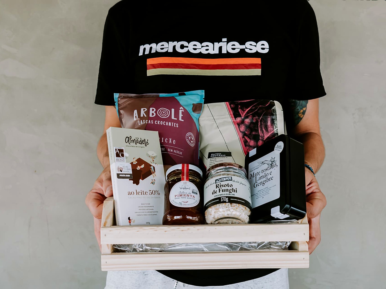 Atendente segurando caixa de presente com chocolate, café, geleia e chás artesanais