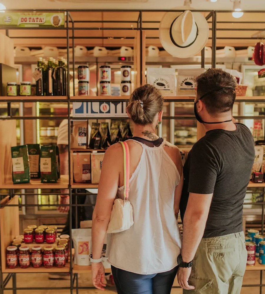 Casal observando as prateleiras de produtos artesanais na unidade Asa Norte