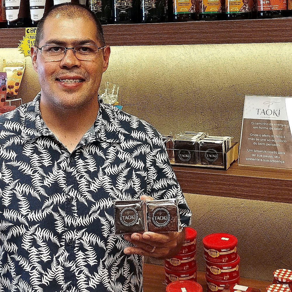 Produtor de brownies artesanais junto à sua vitrine na loja
