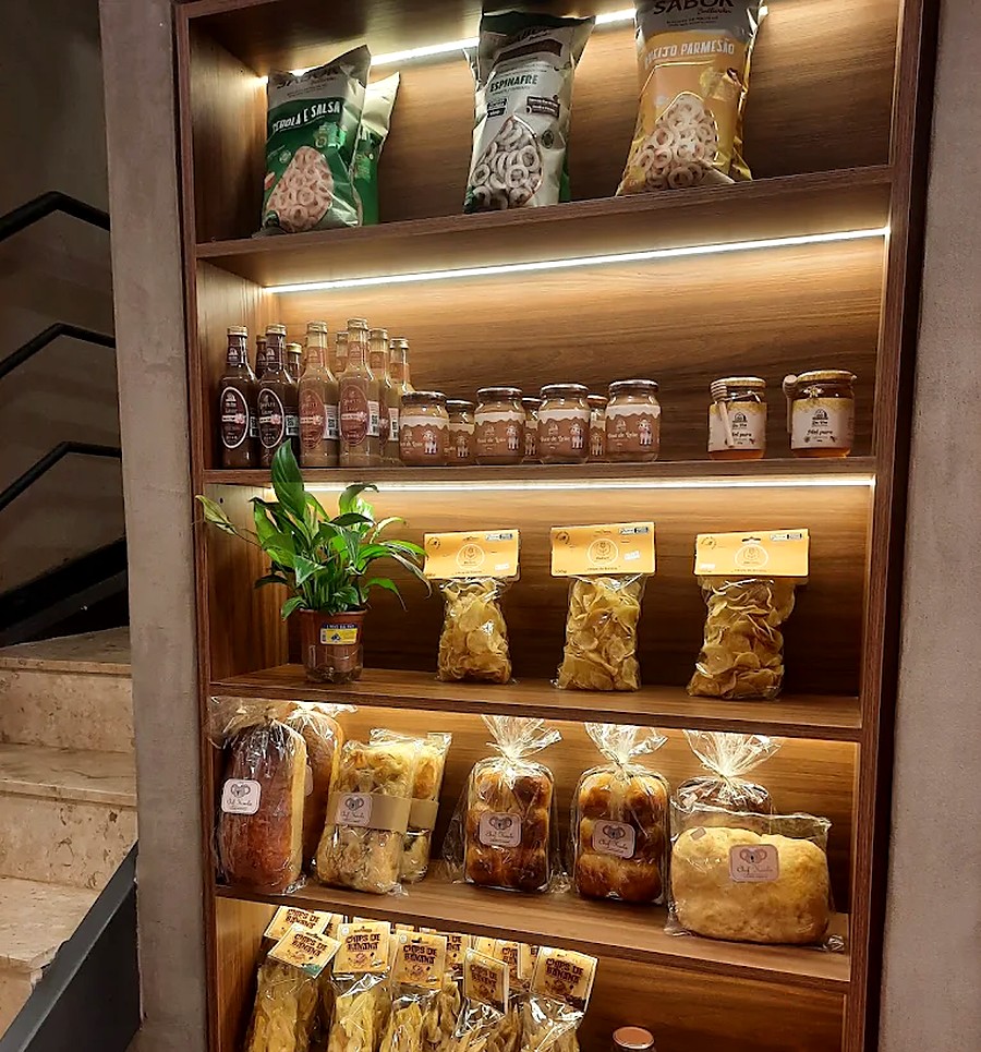 Nichos iluminados com chips, pães, conservas e bebidas artesanais na unidade Asa Sul